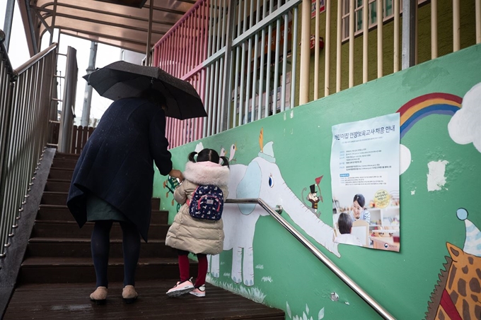 신종 코로나바이러스 감염증(코로나19) 위기경보가 '심각' 단계로 조정됨에 따라 서울시 어린이집이 휴원에 돌입한 25일 서울시내 한 국공립 어린이집에서 한 학부모가 긴급돌봄을 위한 자녀를 등원시키고 있다. 뉴스1