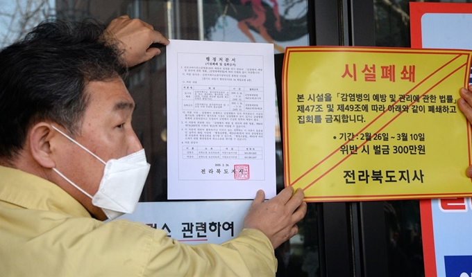 지난 26일 전북 전주시 신천지 하늘문화센터에서 전라북도 관계자들이 '감염병 예방 및 관리에 관한 법률'의 행정명령을 집행해 시설을 폐쇄하고 스티커를 붙이고 있다. 뉴시스.