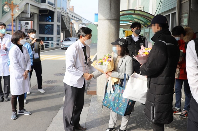 의료진이 대구 중구 서문시장 앞 계명대 대구동산병원서 29일 오후 신종코로나바이러스감염증(코로나19)로 입원, 치료하다 완치판정을 받고 퇴원하는 사란들에게 꽃다발을 전달하고 있다. 계명대 동산의료원 제공