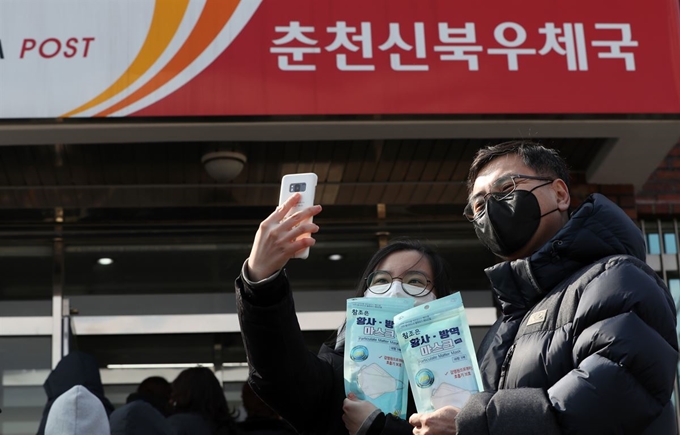 2일 오전 강원 춘천시 신북읍 우체국에서 정부가 공급하는 보건용 마스크를 산 시민들이 스마트폰으로 인증샷을 남기고 있다. 연합뉴스