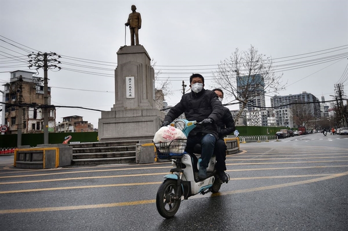 스쿠터를 탄 2명의 남성이 3일 중국 후베이성 우한의 텅빈 거리를 달리고 있다. 우한=AFP 연합뉴스