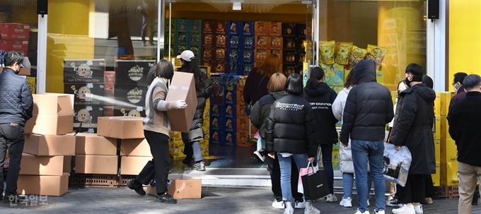 5일 서울 중구 명동의 한 과자 전문점 앞에서 KF94 마스크를 상자 째 쌓아놓고 개당 4,000원에 판매하던 직원이 취재가 시작되자 상자를 매장 안으로 옮기고 있다. 출입구 앞에서 마스크를 구입하기 위해 줄을 선 사람들이 이 장면을 지켜보고 있다. 서재훈 기자