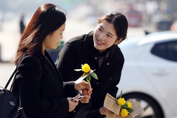 지난해 3월 8일 세계 여성의 날을 맞아 한국여성의전화 관계자가 서울 종로구 광화문 광장에서 시민들에게 노란 장미를 건네주고 있다. 뉴시스