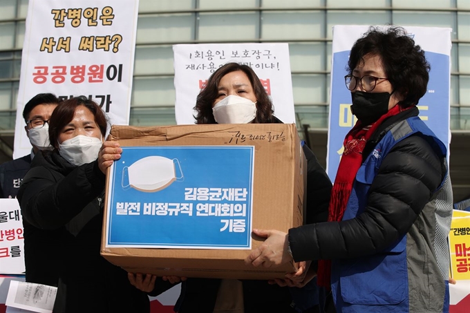 김미숙 김용균재단 대표가 6일 오전 서울 종로구 서울대병원 앞에서 열린 기자회견에서 서울대병원의 간호사, 간병인에게 마스크를 전달하고 있다. 연합뉴스