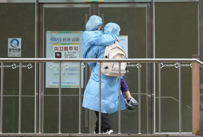 7일 오후 광주 남구 빛고을전남대병원에서 대구에서 온 코로나19 확진자가 거동이 불편한 자녀를 직접 안아 옮기고 있다. 광주=연합뉴스