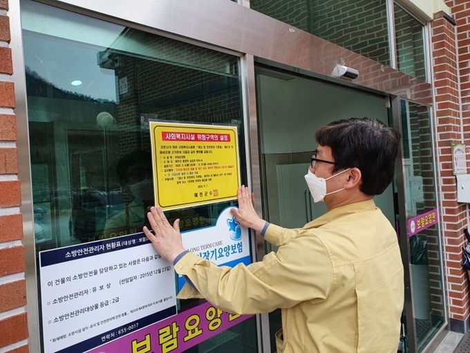 경북 예천군 관계자가 9일 관내 한 요양시설에 코호트 격리시설임을 알리는 안내문을 현관 문에 붙이고 있다. 예천군 제공