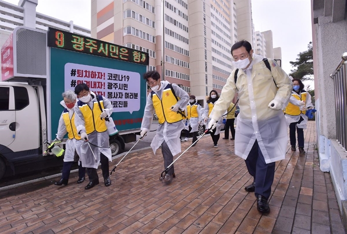 지난 10일 이용섭(맨 오른쪽)광주시장과 자원봉사자 30여명이 광주 서구 쌍촌주공아파트 입구에서 이동방역봉사차량과 함께 방역을 하고 있다. 광주시 제공/2020-03-11(한국일보)