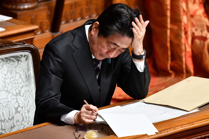 아베 신조 일본 총리가 11일 열린 참의원 본회의에 참석해 자료를 읽어 보고 있다. 도쿄=AFP 연합뉴스