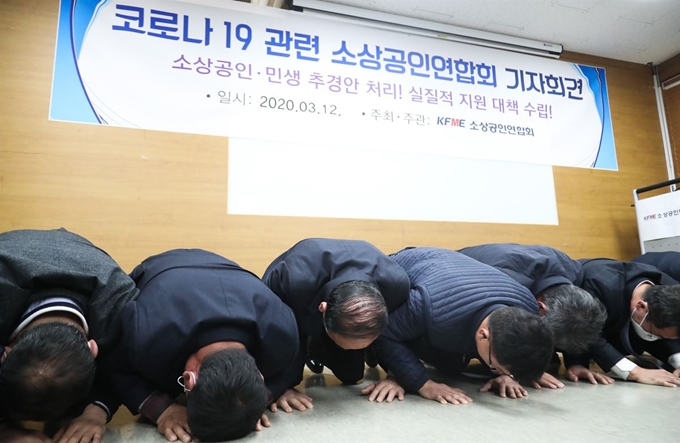 12일 서울 동작구 소상공인연합회에서 열린 ‘신종 코로나바이러스 감염증(코로나19) 소상공인 피해 사례 관련 긴급 기자회견’에서 참석자들이 생존권 보장을 촉구하며 큰절을 하고 있다. 연합뉴스