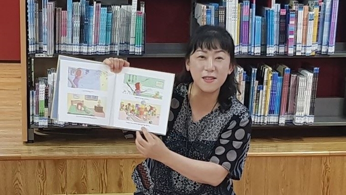 전남 광양시 광양동초등학교 1학년1반 담임인 김영숙 교사가 어린이들과 함께 펴낸 동시집 ‘나랑 자고 가요’를 들고 기념촬영을 하고 있다. 김 교사 제공