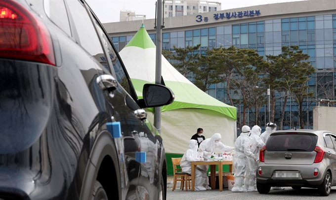 13일 세종시 정부세종청사 근처에 설치된 드라이브 스루 선별진료소에서 시민들이 차를 탄 채 검사를 받고 있다. 세종시는 정부세종청사 해양수산부를 중심으로 교육부, 국가보훈처 등 중앙부처 공무원들의 신종 코로나바이러스 감염증(코로나19) 확진자가 이날 드라이브 스루 선별진료소를 설치했다. 세종=연합뉴스