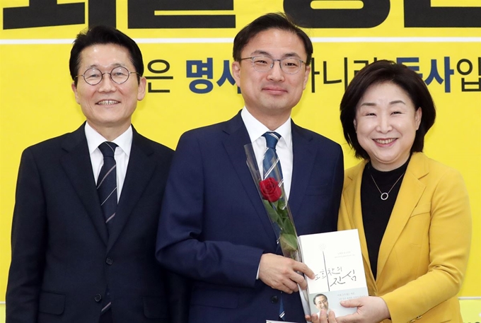 심상정 정의당 대표와 윤소하 원내대표가 8일 서울 여의도 국회에서 열린 21대 국회의원 총선거 비례대표 후보자 선출보고회에서 비례대표 6번에 선정된 신장식(가운데) 당 사법개혁특위원장 에게 장미꽃과 노회찬 회고록을 전달하고 있다. 2020.3.8/뉴스1