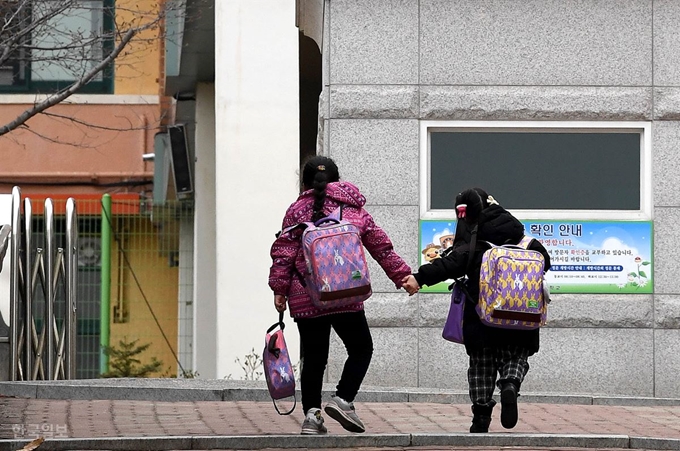 교육부가 코로나19 확산 방지를 위해 전국학교 개학을 2주 더 미뤄 오는 4월 6일로 연기됐다. 4월 개학은 사상 처음이다. 이날 시내의 한 초등학교 돌봄교실에 출석하는 자매가 들어서고 있다. 서재훈 기자 spring@hankookilbo.com