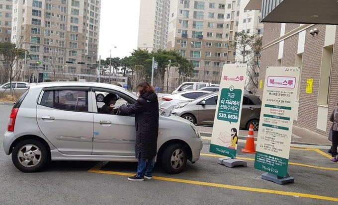 아산 중앙도서관 직원이 도서관 주차장에서 온라인 대출신청한 시민에게 책을 전달하고 있다. 아산시 제공