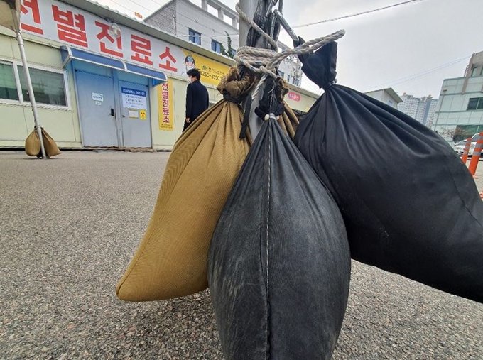 강풍특보가 발효된 19일 강원 춘천시 보건소 광장에 설치된 코로나19 선별진료소 앞 설치물에 강풍에 대비하기 위한 모래주머니가 매달려 있다. 춘천=연합뉴스