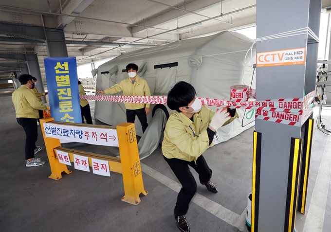 전국 곳곳에 강풍특보가 발효된 19일 오전 광주 북구 공용주차장에 마련된 코로나19 '드라이브 스루' 선별진료소에서 북구청 직원들이 강풍 피해를 예방하기 위해 안전선을 설치하고, 모래주머니를 준비하고 있다. 광주=연합뉴스