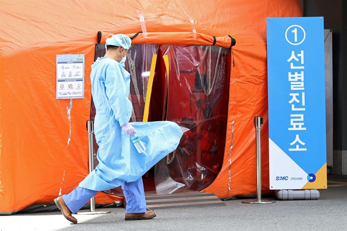 전국에 강풍 경보가 발효된 19일 오후 서울 종로구 강북삼성병원에 마련된 선별진료소 앞을 지나가는 의료진의 의료가운이 바람에 펄럭이고 있다. 연합뉴스