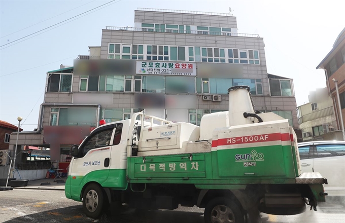 지난 19일 신종 코로나 바이러스감염증(코로나19) 확진자 1명이 발생한 경기 군포시 효사랑요양원에서 하루 만에 확진자 4명이 추가로 발생했다. 지난 20일 오전 경기도 군포시 효사랑요양원(4~5층)이 입주한 건물 앞 도로를 방역차가 소독하는 모습. 연합뉴스