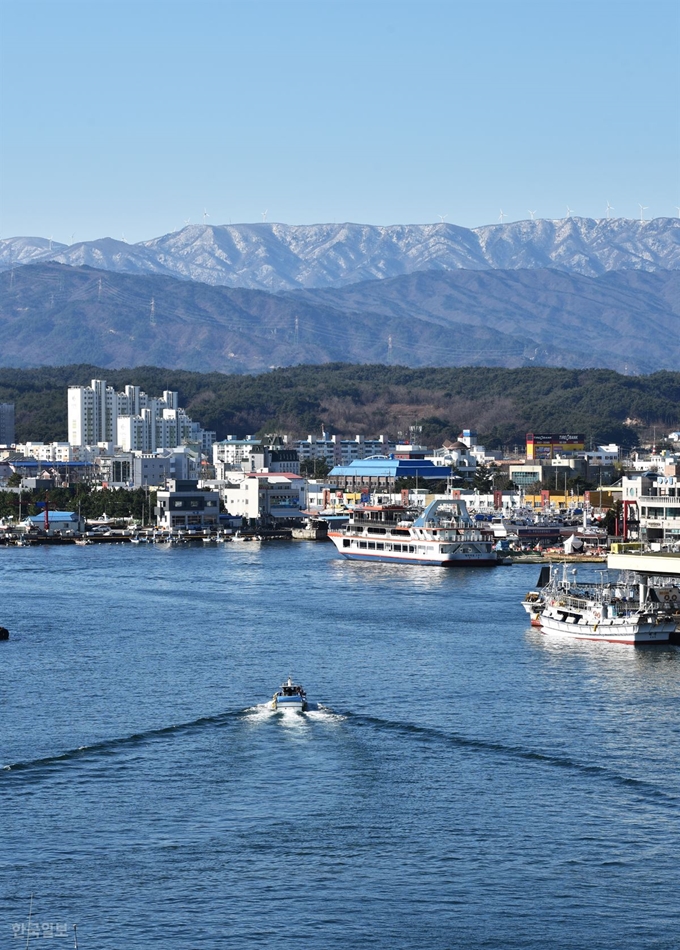 주문진 성황당 뒤편 ‘등대꼬댕이공원’에서 내려다보는 주문진항 풍경. 배가 드나드는 항구를 눈 덮인 선자령이 그림처럼 감싸고 있다.