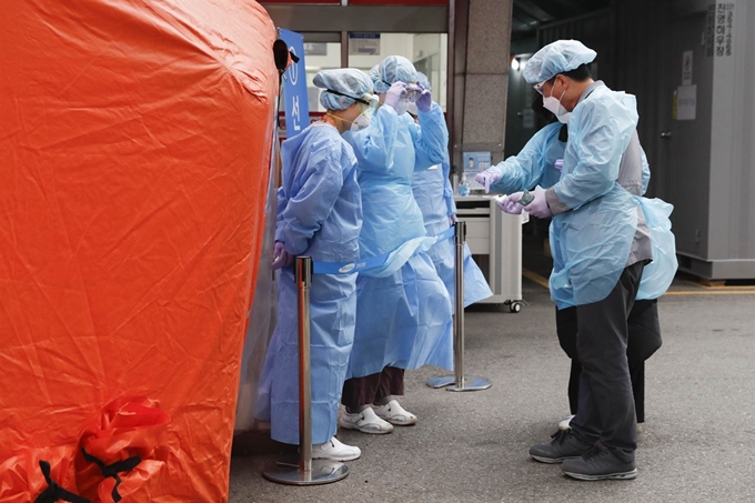 전국적으로 강풍주의보가 발효된 19일 오전 서울 종로구 강북삼성병원 의료진의 일회용 방수 가운이 바람에 날리고 있다. 중앙방역대책본부는 선별진료소등 검체 채취시에 검진 지체현상을 방지하기 위해 전신보호복 대신 오염이 간접 전파되는 것을 막는 용도의 일회용 가운 착용을 권장했다. 뉴시스