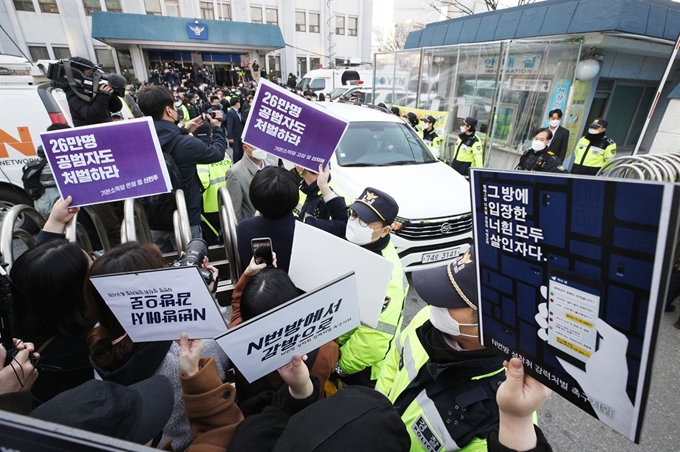 '박사방' 운영자 조주빈(25)이 25일 서울 종로구 종로경찰서 유치장에서 나와 검찰로 송치되는 동안 시민과 사회 정치 단체 회원들이 규탄 피켓을 흔들고 있다. 이날 경찰은 국민의 알권리, 동종범죄 재범방지 및 범죄예방 차원에서 신상을 공개했다. 고영권 기자