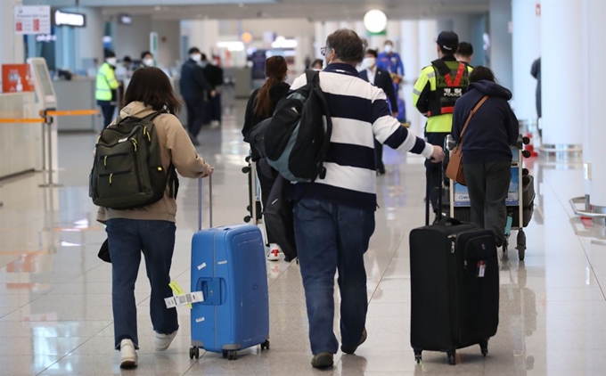 영국 런던발 항공편으로 입국한 외국인들이 24일 오후 인천국제공항 2터미널에 도착해 경찰의 인솔을 받아 임시생활시설로 향하는 버스를 타기 위해 이동하고 있다. 연합뉴스