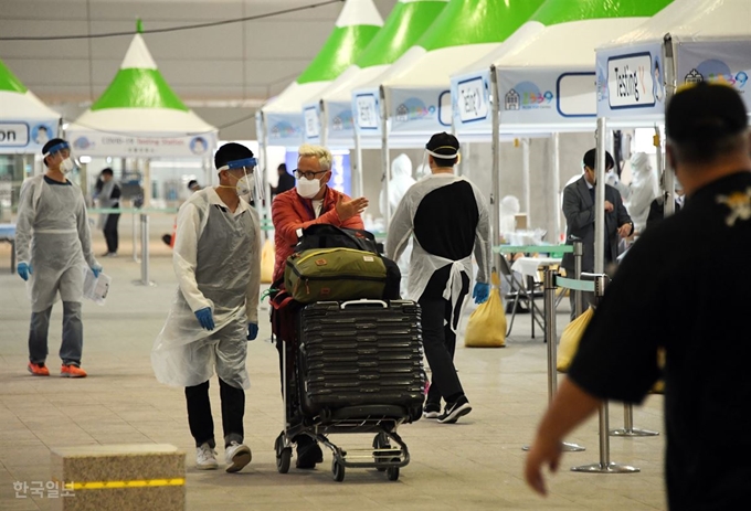 26일 오후 인천공항 제2터미널에서 런던발 항공기에서 내린 한 외국인이 코로나19 검체 검사를 받은 뒤 방역요원과 대화하고 있다. 영종도=고영권 기자