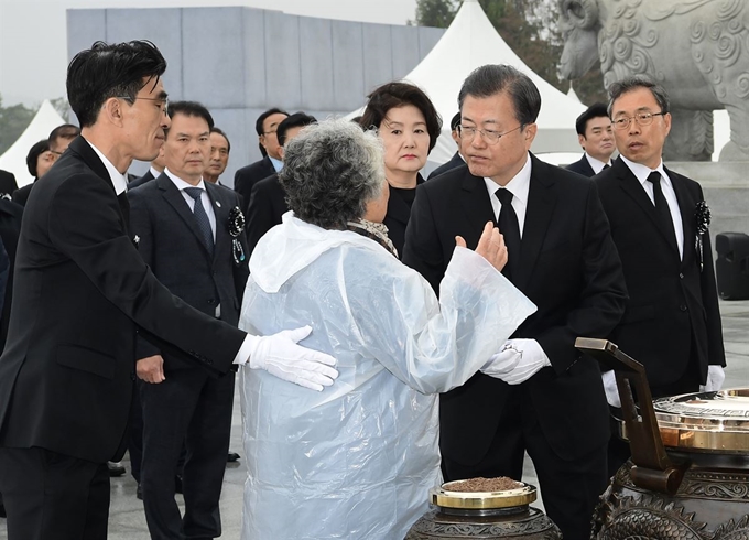 문재인 대통령이 27일 국립대전현충원에서 열린 서해수호의 날 기념식에서 분향하던 중 유가족의 질문을 듣고 있다. 유가족이 대통령에게 "천안함 폭침 누구 소행인지 말씀해 달라, 늙은이 한 좀 풀어달라"고 호소했다. 문 대통령은 "정부의 공식 입장에는 한치의 변함이 없다"라며 "걱정 마시라"고 말한 후 분향을 이어갔다. 연합뉴스