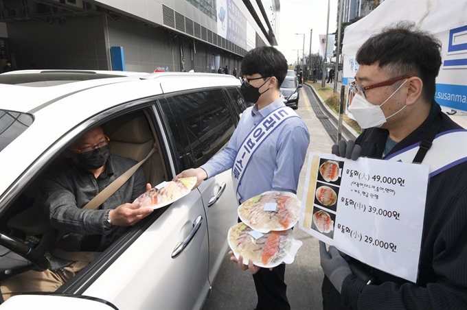 서울 동작구 노량진 수산시장에서 운전자가 차에 탄 채 회를 주문하고 있다. 노량진 수산시장은 신종 코로나바이러스 삼염증 확산 여파로 '드라이브 스루' 판매장을 지난 26일부터 운영하고 있다. 연합뉴스