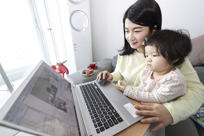 재택근무를 시작한 KT 직원이 집에서 아이를 돌보며 화상회의 시스템을 활용해 업무를 보고 있다. 한국일보 자료사진