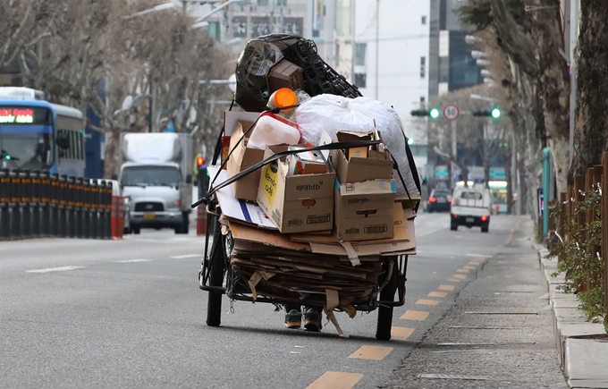 지난달 26일 오전 대구 북구 경대교 인근 도로에서 한 노인이 수레 가득 파지를 싣고 무거운 발걸음을 옮기고 있다. 대구=뉴스1