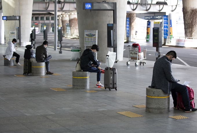 6일 오전 인천국제공항 제1여객터미널 입국장에서 버스를 기다리는 입국자들이 떨어져 앉아 있다. 연합뉴스