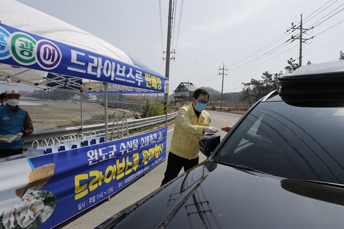 신우철 전남 완도군수가 지난 5일 완도읍 도로에서 열린 수산물 드라이브 스루 판매행사에서 주민에게 물건을 팔고 있다. 완도군 제공