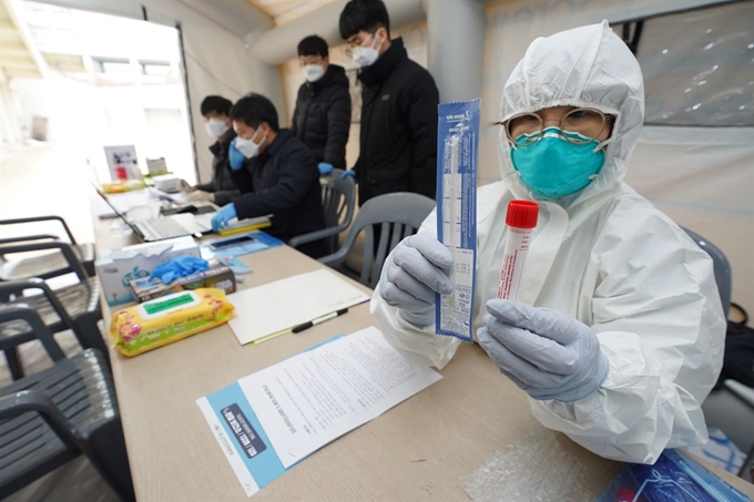 지난 3일 서울 마포구 홍익대에 설치된 선별진료소에서 방호복을 입은 마포구 직원이 검사 키트를 들어 보이고 있다. 연합뉴스