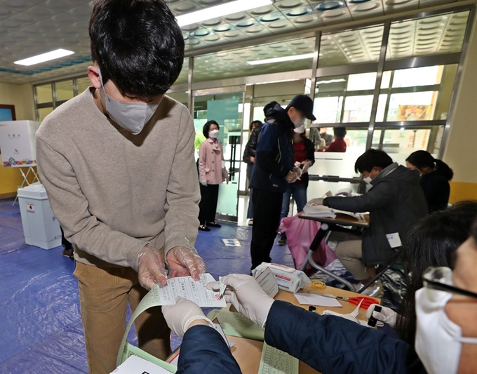 제21대 국회의원 선거일인 15일 오전 청주시 서원구 샛별초등학교에 마련된 산남동 제5투표소에 유권자가 투표용지를 받고 있다. 연합뉴스