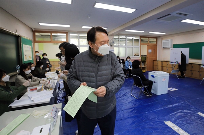 윤석열 검찰총장이 제21대 국회의원선거일인 15일 오전 서울 서초구 원명초등학교에 마련된 투표소에서 기표소로 향하고 있다. 2개월 여 만에 언론 카메라에 포착된 윤 총장은 이날 홀로 투표소를 찾아 마스크를 쓴 채 한 표를 행사했다. 뉴스1