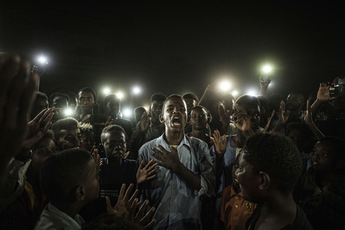 네덜란드 암스테르담에 본부를 둔 '세계보도사진(World Press Photo)' 재단이 16일 발표한 수상작 중 '올해의 사진상'에 선정된 AFP 통신의 치바 야스요시가 촬영한 '진실한 음성'. 이 사진은 민주화 운동 중이던 지난해 6월 19일 수단 카르툼에서 정전 속에 민주화를 요구하는 구호를 외치는 시위 중 시낭송을 하고 있다. 세계보도사진=AP연합뉴스