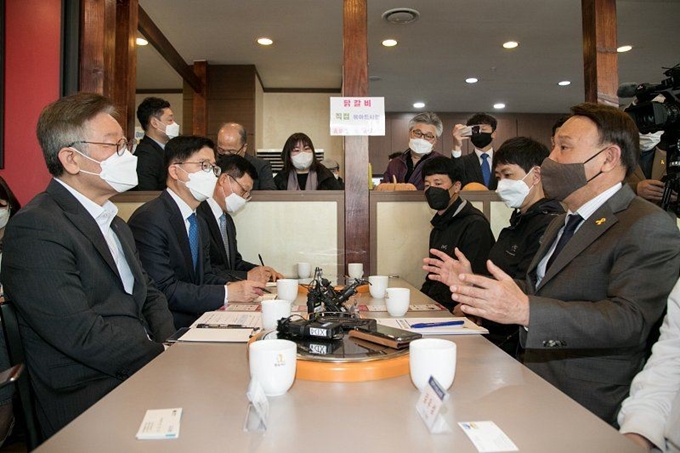 이재명(왼쪽) 경기지사가 17일 전북 군산시를 찾아 강임준(오른쪽) 군산시장, 소상공인 등과 공공 배달앱에 대해 대화를 나누고 있다. 군산시 제공