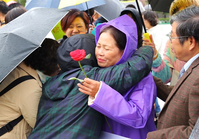 베트남전 종전 43주년인 2018년 4월 23일 오전, 서울 종로구 청와대 분수대 앞에서 열린 '미안해요, 베트남' 릴레이 마감 기자회견에서 베트남전 당시 한국군 민간학살 피해자인 퐁니마을의 응우옌티탄 씨에게 회견 참석자들이 사과와 위로의 꽃을 전달하고 있다. 연합뉴스