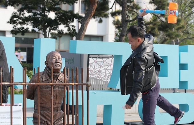 25일 오후 광주 동구 5ㆍ18민주광장에서 뿅망치를 든 5ㆍ18 단체 관계자가 ‘전두환 구속 동상’을 향해 힘껏 내리치고 있다. 연합뉴스