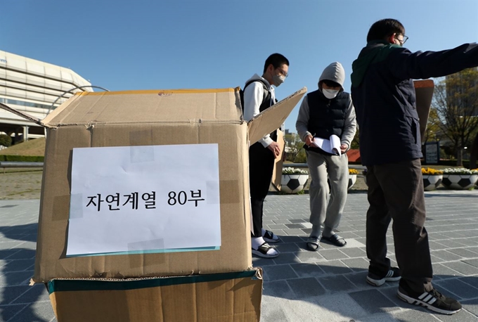 부산동인고 교사들이 지난 24일 부산 동래구 사직조각공원 앞에서 고3 전국연합학력평가 문제지를 드라이브 스루 방식으로 학생들에게 배부하고 있다. 부산=연합뉴스