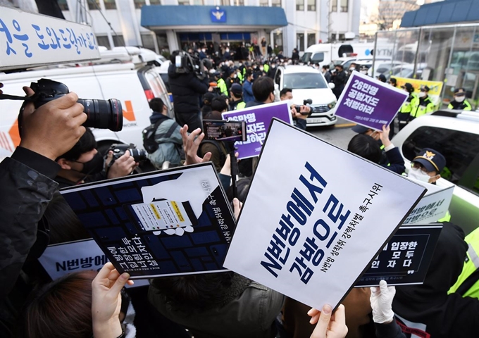 지난 3월 ‘박사방’ 운영자 조주빈이 탄 차량이 서울 종로경찰서를 나와 검찰 유치장으로 향하자 시민들이 조주빈의 강력처벌을 촉구하며 피켓 시위를 하고 있다. 연합뉴스