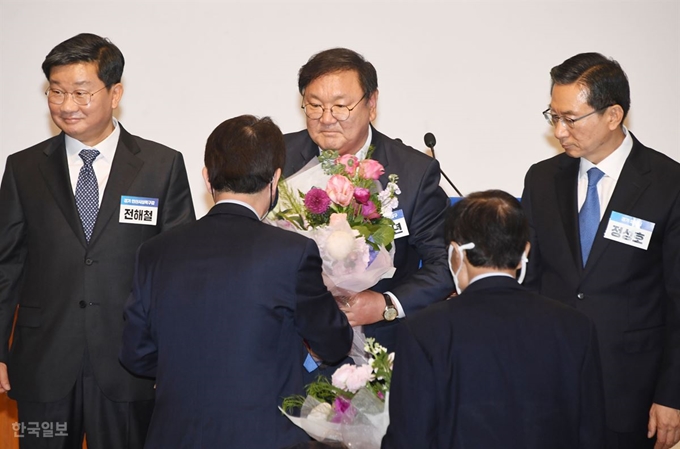 7일 국회 의원회관에서 열린 더불어민주당 당선인 총회에서 21대 국회 첫 원내대표로 뽑힌 김태년(가운데) 의원이 전임 이인영 원내대표로부터 축하 꽃다발을 받고 있다. 오대근 기자