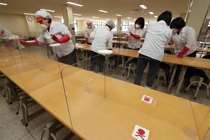 경북 칠곡군 왜관읍 왜관초등학교 급식실에서 학교 관계자들이 지난달 25일 신종 코로나바이러스 감염증(코로나19) 확산방지를 위해 설치한 투명 가림막과 식탁 등을 청소하고 있다. 연합뉴스