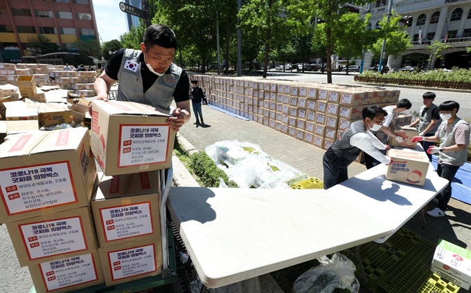 8일 서울 영등포구 여의도순복음교회 앞 광장에서 이 교회 신도와 국제 구호 단체 '굿피플' 자원봉사자 들이 코로나19 여파로 생활 형편이 더 어려워진 독거노인과 기초생활수급자 5,000가구에 전달할 생필품 패키지 '희망박스'를 옮기고 있다. 뉴시스