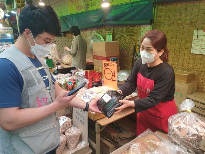 전통시장 실시간 배달 어플리케이션(앱) '놀장(놀러와요 시장)'의 직원 유성요씨가 7일 경기 광명시 광명전통시장에서 고객이 주문한 음식을 상인으로부터 전달받으며 확인하고 있다. 윤태석 기자 sportic@hankookilbo.com