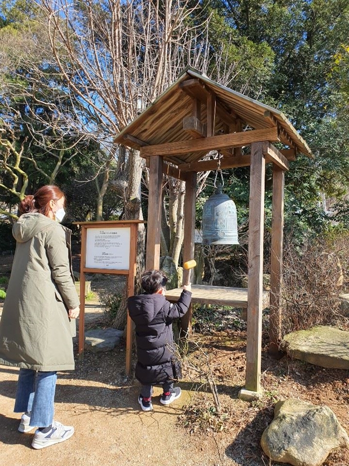 해창 주조장을 방문한 한 관광객 가족이 정원에 마련된 주신을 부르는 종을 치고 있다