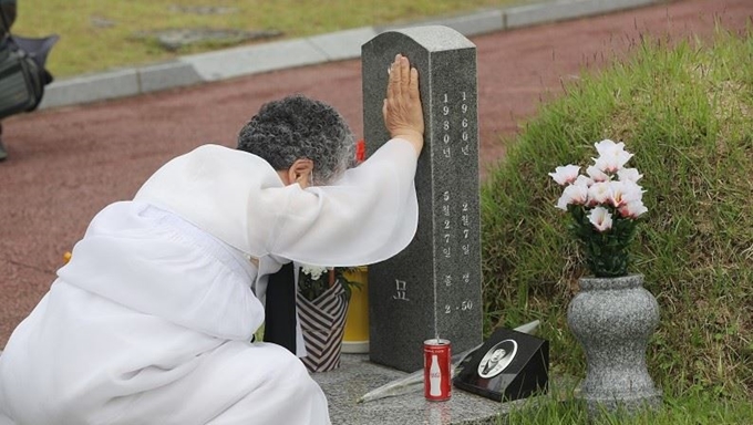 5ㆍ18민주화운동 40주년을 하루 앞둔 17일 오전 광주 북구 국립5ㆍ18민주묘지에서 희생자 유가족이 묘비를 만지며 눈물을 흘리고 있다. 연합뉴스