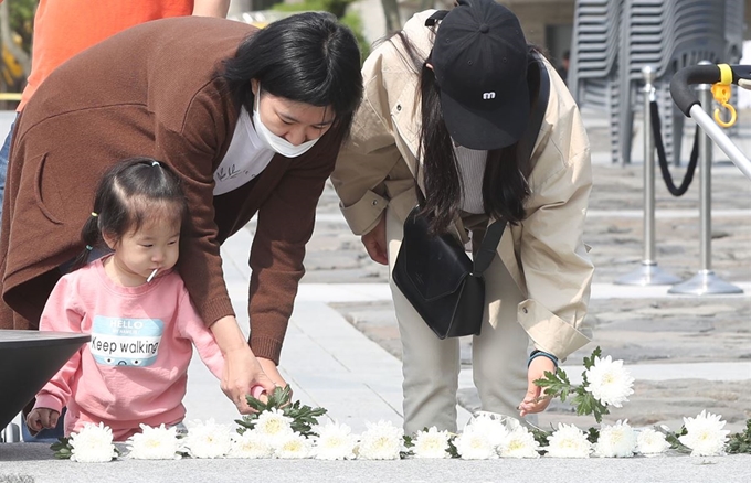 노무현 전 대통령 11주기 추도식을 하루 앞둔 22일 오전 경남 김해 봉하마을을 찾은 시민과 어린이가 노 전 대통령 묘역에 헌화하고 있다. 연합뉴스