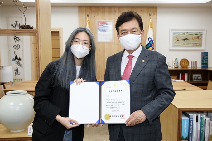 김병우(오른쪽)충북교육감은 25일 교육감실에서 학교 밖 배움으로 학력을 인정받은 신모양에게 중학교 졸업증서를 전달한 뒤 노고를 위로했다. 충북도교육청 제공